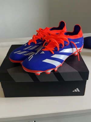  Helt nya Adidas Predator MC skor - Säljer ett par Adidas Predator fotbollsskor i blått med vita detaljer format som klassiska stripes och orangea snören samt innersula, aldrig användts och i ny skick 