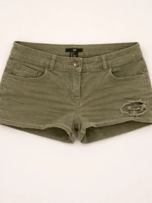Olivgröna shorts från H&M - Snygga olivgröna shorts från H&M med råa kanter och slitning på ena benet. Klassisk femficksmodell med knapp och dragkedja framtill. Perfekta för varma dagar och enkel att matcha med olika toppar.