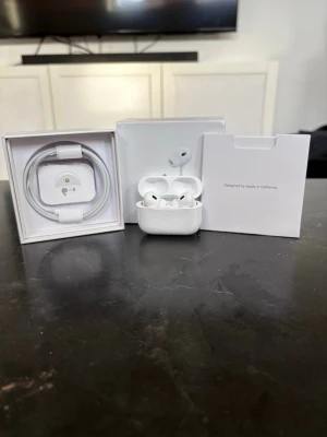 Apple AirPods Pro med laddningsetui - Säljer ett par vita Apple AirPods Pro med trådlöst laddningsetui. Hörlurarna har en stilren och kompakt design i blank plast och levereras med originalförpackning, laddningskabel och dokumentation. Perfekta för dig som vill ha grymt ljud och smidig anslutning till din iPhone.