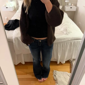 Mörkblå bootcut jeans med kontrastsömmar - Snygga mörkblå bootcut jeans med vita kontrastsömmar och klassisk femficksdesign. Jeansen har normal passform och låg midja, perfekta till en avslappnad stil. Materialet känns som bomull med lite stretch för extra komfort.