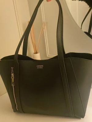 Guess väska - Säljer denna super snygga väskan från GUESS.Man får med en liten väska till som kom med den. Använd många gånger men ett väldigt bra skick. Pris kan diskuteras 