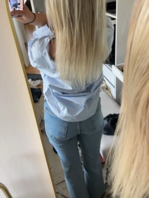 Ljusblå oversized skjorta med knappar - Säljer en ljusblå oversized skjorta med bruna knappar och v-ringning. Skjortan har vida trekvartsärmar och är tillverkad i ett mjukt bomullstyg. Perfekt för en chill och avslappnad look. Ifrån Zara och slutsåld. Tröjan har fläckar på ryggen inget jag har fått bort 