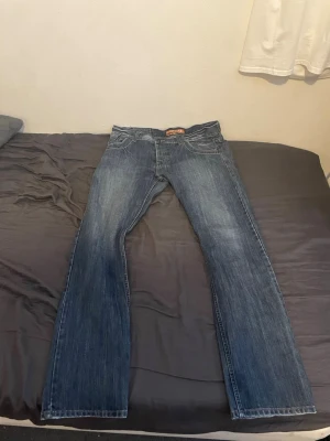 Blå bootcut jeans från select lime - Säljer ett par klassiska blå bootcut jeans från select line med snygg slitning och kontrastsömmar. Jeansen har fem fickor och en bekväm passform med normal midja. Perfekta för dig som gillar en avslappnad men ändå stilren look.