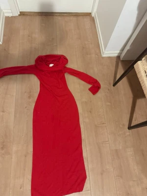 Röd långärmad långklänning - Snygg röd långklänning med långa ärmar och polokrage. Klänningen har en enkel, rak passform och är tillverkad i ett mjukt, stretchigt material som känns bekvämt mot huden. Perfekt för dig som vill sticka ut med en färgstark look.