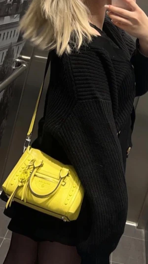 Gul handväska från Michael Kors - Säljer en snygg gul handväska från Michael Kors i läder. Väskan har både handtag och axelrem, silverfärgade detaljer och dekorativa nitar på sidorna. Perfekt storlek för det viktigaste och ger en färgklick till din outfit.