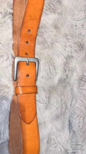 Klassiskt brunt skärp i skinn - Snyggt brunt bälte i skinn med silverfärgat metallspänne. Enkel och stilren design som passar till jeans eller byxor. Bältet har flera hål för justerbar passform och en bredare rem för en tidlös look.