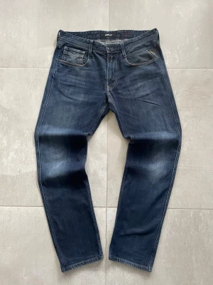 Mörkblå jeans från Replay - Snygga mörkblå jeans från Replay med klassisk femficksmodell och diskreta slitningar på låren. Jeansen har raka ben och kontrastsömmar som ger en stilren look. Tillverkade i mjukt denimtyg som sitter skönt hela dagen.