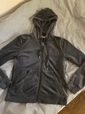 Mörkgrå zip hoodie med huva - Snygg mörkgrå hoodie med dragkedja framtill och stora fickor. Tillverkad i mjukt, sammetsliknande material och har justerbara snören i huvan. Perfekt för en avslappnad och trendig look.