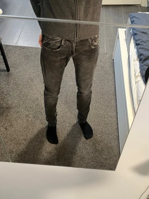 Svarta Replay anbass i slim fit jeans med slitningar - Säljer ett par svarta slim fit jeans med snygga slitningar och tvättade detaljer. Jeansen har klassisk femficksmodell och normal midja. Perfekta för dig som gillar en modern och avslappnad stil.