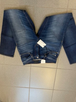 Blåa tiger of Sweden jeans  - Säljer ett par klassiska blå jeans från tiger of Sweden med slim ben  och femficksmodell. Jeansen har snygga slitningar framtill och kontrastsömmar. Tillverkade i denim med en tidlös tvätt och passform som funkar till allt.