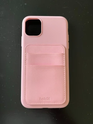 Rosa mobilskal med kortfack Holdit - Snyggt rosa mobilskal från Holdit med två praktiska kortfack på baksidan. Skalet är gjort i mjukt silikonmaterial och har en stilren design som passar perfekt till vardagen. Perfekt för dig som vill ha både skydd och plats för kort i ett.