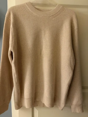 Maison margiela tröja  - Säljer en beige stickad tröja från Maison Margiela. Tröjan har en rak passform, rund halsringning och ribbstickade muddar. Tillverkad i ett mjukt material som känns lyxigt och passar perfekt till lager på lager-stil.