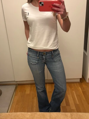 Blå bootcut jeans från soccx - Säljer ett par ljusblå bootcut jeans från soccx med fickor på framsidan. Jeansen är låg midjade. 