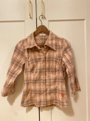 Figursydd skjorta  - Figursydd rosa grön rutig skjorta med trekvarts ärmar.💗