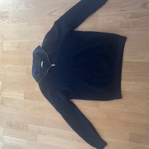 Marinblå ziptröja från Zara - Mörkblå ribbstickad tröja från Zara med hög krage och dragkedja framtill. Tröjan har lång ärm och är tillverkad i ett mjukt, tjockare material som passar perfekt för kyligare dagar. Storlek M använd mycket men inga skador eller slitningar🤩🙌