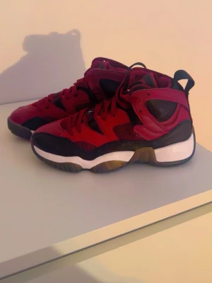 Röda och svarta high top sneakers - Snygga sneakers i high top-modell med röd ovandel, svarta detaljer och vit sula. Skorna har en sportig design med perforerade partier och kraftig yttersula. Perfekta för dig som vill sticka ut med färg och stil.