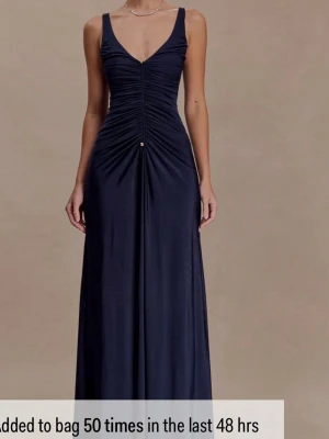 Marinblå långklänning med rynk från Meshki - Säljer denna eleganta marinblåa långklänning med djup v-ringning och rynkade detaljer framtill. Den är helt oanvänd och har lappen kvar! Klänningen har smala axelband och en figurnära passform upptill som övergår i en lätt utsvängd kjol. Perfekt för speciella tillfällen. Super snygg! 
