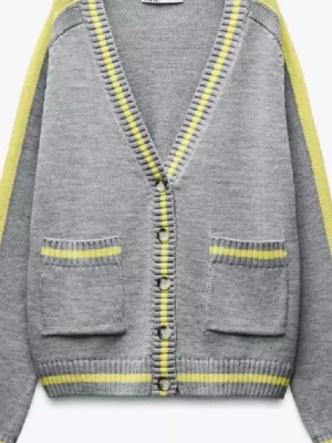 Grå kofta med gula detaljer - Snygg grå kofta med knappar och två fickor framtill. Gula ränder längs kanter, ärmar och fickor ger ett fräscht och trendigt intryck. Koftan har ribbstickade muddar och en djup v-ringning. Perfekt för lager-på-lager och att matcha med jeans.