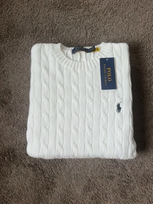 Vit kabelstickad tröja Polo Ralph Lauren - Kabelstickad vit tröja från Polo Ralph Lauren. Helt ny, storlek S. Passar dig som vill ha en klassik och stilren look. Vid frågor eller funderingar tveka inte på att höra av er mvh 😁