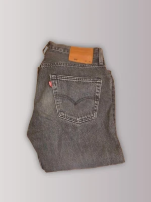 Levi's 501 - Beskrivning  Klassiska Levi’s 501-jeans i tvättad svart / mörkgrå färg. Rak passform med button fly.  Skick: Som nya, endast använda en eller två gånger. Inga synliga defekter.  Material: 100 % bomullsdenim.  Storlek: Märkt storlek: W30 L34  Mått (plagget ligger plant):  Midja: 40 cm  Innerbenslängd: 27 cm  Ytterbenslängd: 108 cm  Lårbredd: 38 cm  Benöppning: 19 cm   Skicka gärna ett meddelande om du har några frågor. Pris är förhandlningsbart.