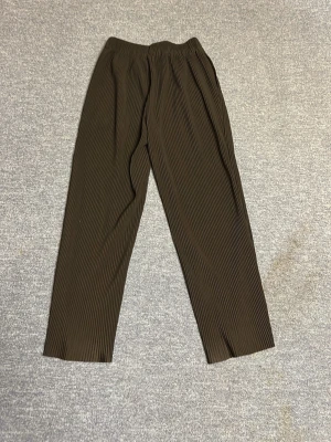 Bruna plisserade mjukisbyxor - Snygga bruna mjukis med plisserad struktur och rak passform. De har resår i midjan för extra komfort och är tillverkade i ett mjukt, stretchigt material. Perfekta för en trendig och avslappnad look.