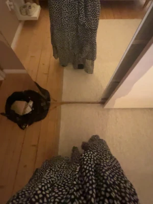 Svart långkjol med vita prickar - Säljer en svart långkjol med vita prickar och volangdetaljer. Kjolen har en flowy passform och är perfekt för dig som gillar en avslappnad men ändå trendig stil. Materialet känns lätt och skönt mot huden.