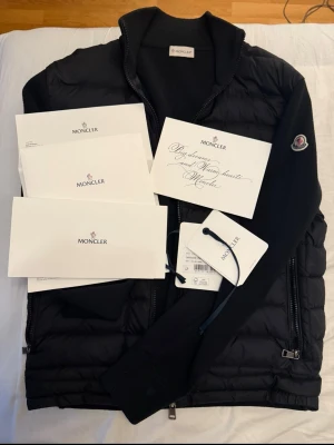 Moncler Tricot Cardigan (M) - Autentisk jacka från Moncler perfekt nu till våren. Alla tags följs med. Digitalt kvitto finns tillgänglig. Jag kan frakta säkert med PostNord. Tar endast emot Swish. Storlek: M. Kör ej här via Plick, kör utanför denna appen.