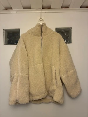 Beige teddyjacka från H&M, XXL - Supermjuk och oversized teddyjacka i beige från H&M. Jackan har hög krage, dragkedja framtill och två stora fickor. Perfekt för att hålla sig varm och se chill ut under kalla dagar. Materialet är fluffigt och ger en riktigt cozy vibe.