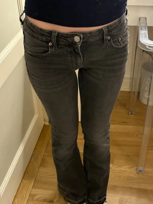 Gråa bootcut jeans med låg midja - Säljer ett par mörk gråa bootcut jeans med låg midja från Gina Tricot. Jeansen har en snygg tvättad look och är tillverkade i ett stretchigt material som sitter skönt. De är i barn storlek 156 men passar mig som vanligtvis har storlek xxs/xs. Byxorna är sprättade längst ner för att ge lite mer längd (de sista bild). Annars är byxorna i fint skick!