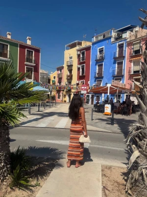 Mönstrad långklänning i orange toner - Säljer en snygg långklänning med färgglada mönster i orange, brunt, vitt och svart. Klänningen är axelbandslös med snörning upptill och har ett bohemiskt, stickat utseende. Perfekt för sommardagar och festivaler.