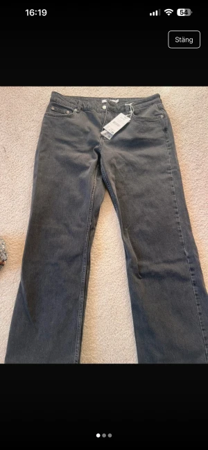 Grå raka jeans från NA-KD - Säljer ett par grå jeans från NA-KD i rak modell med klassisk femficksdesign och bälteshällor. Jeansen är tillverkade i bomull och har en snygg tvättad look. Perfekta för en avslappnad och trendig stil. Ett helt par nya jeans från NA-KD som tyvärr inte passade mig och jag hann inte lämna tillbaka dem innan returtiden gick ut. Helt oanvända, lappen sitter kvar och originalförpackningen finns kvar – kan skickas i den.