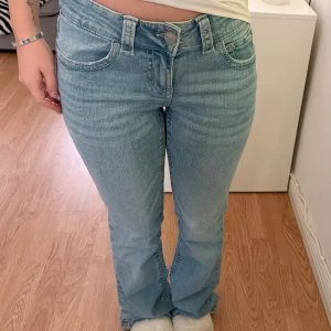 Blå bootcut jeans från Gina Tricot - Säljer ett par ljusblå bootcut jeans från Gina Tricot med klassiska femficksdetaljer och snygga ficklock bak. Jeansen har normal passform och är tillverkade i bomull med en liten mängd stretch för extra komfort.