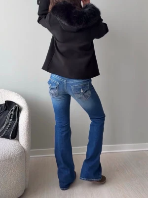 Gina Tricot Jeans lågmidjade bootcut - Snygga blå bootcut jeans från Gina Tricot med klassiska kontrastsömmar och dekorativa fickor bak. Jeansen har låg midja och coola detaljer på fickorna. Perfekt för dig som gillar en avslappnad och trendig look.