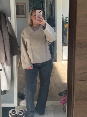 Beige kort kappa💗 - Säljer en beige kappa med omlott-design och vida långärmar. Jackan har en stilren och modern look med mjukt material och diskreta sömmar. Perfekt för dig som gillar minimalistisk stil och vill ha något som sticker ut utan att vara för mycket.💓