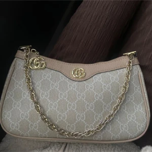 Beige axelväska  - Säljer denna supersöta väskan i väldigt fint skick kommer även med ett rött&grönt band 🏹🤎