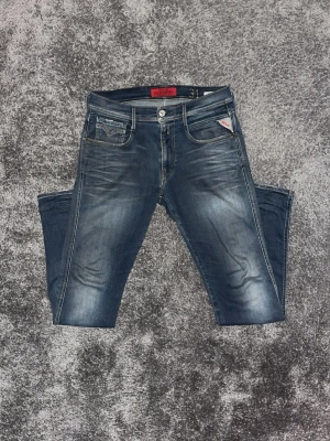 Mörkblå jeans från Replay - Snygga mörkblå jeans från Replay med klassisk femficksdesign och diskreta slitningar framtill. Jeansen har slim-fit passform  och detaljerade bakfickor med Replay-logga. Perfekta för en trendig och avslappnad look.