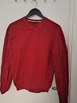 Stickad tröja  - Röd stickad tröja från Atlantis med V-ringning och ribbade muddar vid ärmslut och nederkant. 100% bomull Hittar inga defekter 🩷