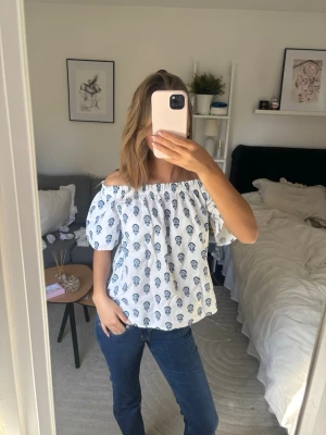 Vit offshoulder blus med blått blommönster - Säljer denna super våriga off shoulder toppen från vero moda. Har super fint mönster och är luftig och skön!💕