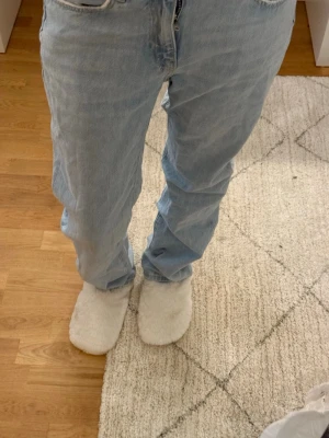 Ljusblå raka jeans - Säljer ett par ljusblå jeans med rak passform och klassisk femficksdesign. Jeansen har mellan midja och är tillverkade i denim. Perfekta för en avslappnad och trendig look.