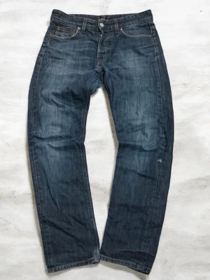 Filippa K jeans  - Säljer ett par mörkblå jeans med klassisk rak passform och fem fickor. Jeansen har subtila slitningar och kontrastsömmar. Tillverkade i denim med en snygg tvättad look. Perfekta för dig som gillar en tidlös och avslappnad stil.