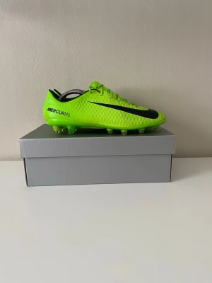 Nike Mercurial limegröna fotbollsskor Elite  - Säljer ett par Nike Mercurial fotbollsskor i en riktigt snygg limegrön färg med svarta detaljer och klassisk swoosh på sidan. Skorna är sparsamt använda. Dobbarna är till för konstgräs men funkar även på gräs. Säljer för att dem är för små. 