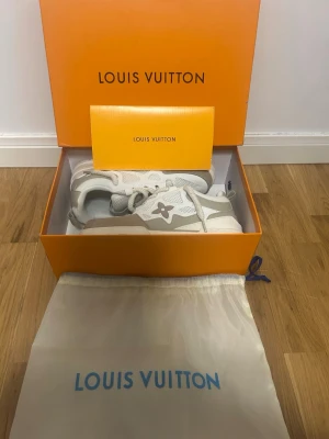 Louis Vuitton vita sneakers - Snygga Louis Vuitton sneakers i vitt och beige med ikoniska LV-blomman på sidan. Skorna har en chunky sula, mesh- och läderdetaljer samt klassiska snören. Kommer i originalkartong och dustbag för extra lyxig känsla.