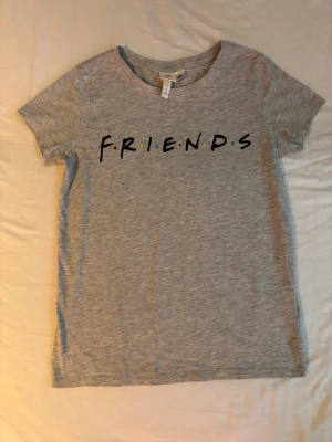 Grå FRIENDS t-shirt från H&M - Säljer en grå t-shirt från H&M med FRIENDS-tryck på bröstet. 