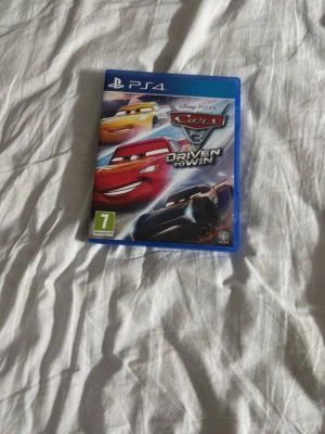 Cars 3 Driven to Win till PS4 - Säljer spelet Cars 3: Driven to Win till PlayStation 4. Omslaget är blått och har färgglada bilar från filmen Cars på framsidan. Spelet är ett racingspel där du kan tävla med karaktärer som Lightning McQueen. Perfekt för dig som gillar fartfyllda bilspel.