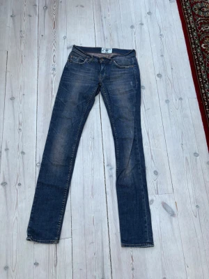 Blå raka jeans från Tiger of Sweden  - Snygga blå jeans från Tiger of Sweden Jeans med rak passform och klassisk femficksdesign. Jeansen har subtila slitningar och kontrastsömmar, vilket ger en avslappnad men stilren look. Tillverkade i denim med en autentisk tvättad finish.