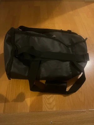 HUGO BOSS Parfums Weekendbag / Träningsväska - Snygg och stilren weekendbag från HUGO BOSS i svart. Perfekt som träningsväska, weekendbag eller kabinväska för kortare resor. Väskan har en rymlig huvudficka med dragkedja samt justerbar axelrem och bärhandtag för bekväm transport. Den är i bra skick. Skicka bara meddelande ifall ni undrar något mer.
