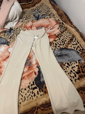 Beige utsvängda byxor Gina Tricot - Säljer ett par beige leggings med utsvängda ben och hög midja. De är stretchiga och har en mjuk känsla, perfekta för en trendig och bekväm look. Passar till många olika stilar och är lätta att matcha med andra plagg. Orginalpris 379kr med prislappen på. 