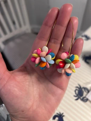 Färggladaf örhängen  - örhängen med  flera färger som rosa, blå, gul, orange och vit. Örhängen är gjorda av små pärlliknande delar och hänger på tunna guldfärgade krokar. Perfekta för dig som vill sticka ut med färg och lekfull stil.