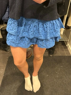 Blå volangkjol med broderade detaljer - Supersöt blå kortkjol med volanger och broderade hålmönster. Köpt i London