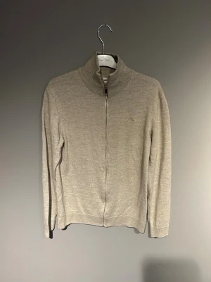 Lindbergh beige ziptröja  - Stilren Lindbergh merinoull stickad ziptröja i beige. Mycket bra skick. Haft den ett tag men knappt använd. Är i storlek L men sitter som M därav ej använd.
